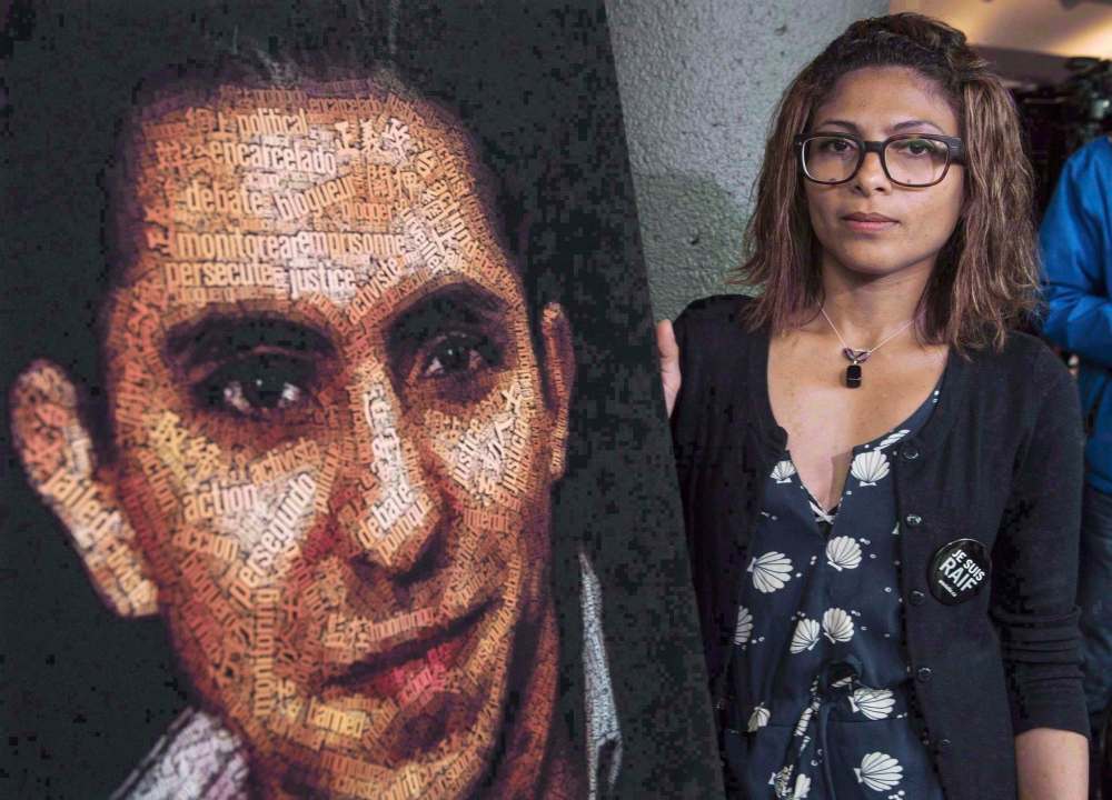 Ensaf Haidar stands next to a poster of a book of articles written by the imprisoned Saudi blogger and Haidar's husband, Raif Badawi, on June 16, 2015 in Montreal. Saudi Arabia is retaliating after Global Affairs Canada tweeted its concern about the arrests of civil society and women's rights activists in Saudi Arabia, including jailed blogger Badawi and his sister Samar Badawi. (Paul Chiasson / The Canadian Press Files)