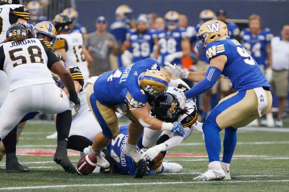 JOHN WOODS / THE CANADIAN PRESS
Bombers linebacker Adam Bighill (centre) forces a fumble from Tiger-Cats running back Alex Green during Friday night’s game at Investors Group Field. Bighill led Winnipeg’s improving defence, finishing with a team-high seven tackles.