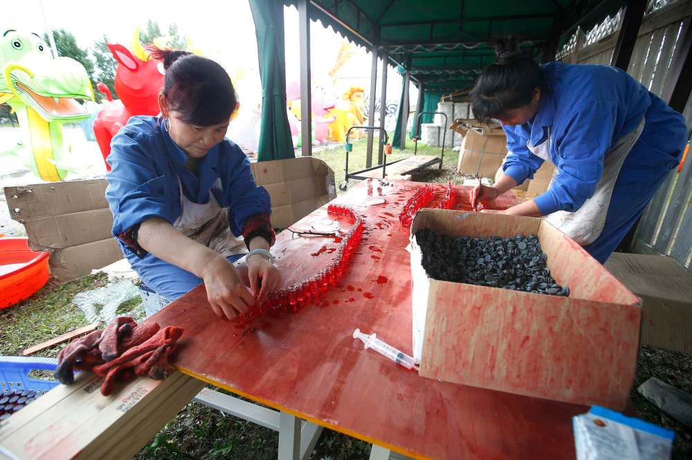 Light artists Shu Fang Zhu (left) and Gui Mei Tu fill bottles with coloured water for a bison light exhibit. (John Woods / Winnipeg Free Press)