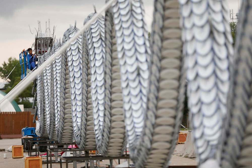 Light artist Jian Wang puts the finishing touches on a 60-metre dragon at the Red River Ex grounds Monday. The Chinese lights festival opens at the end of August to commemorate the 30th anniversary of the twinning between Winnipeg and Chengdu, China. (John Woods / Winnipeg Free Press)