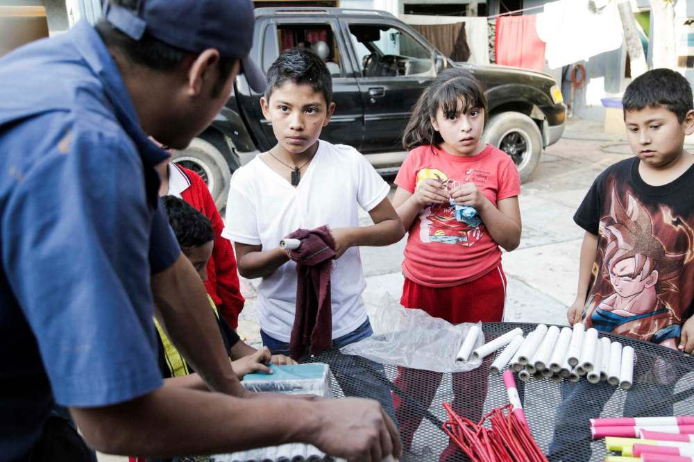 Santi (in white shirt) cleans firework casings with his friends. (Oscilloscope)