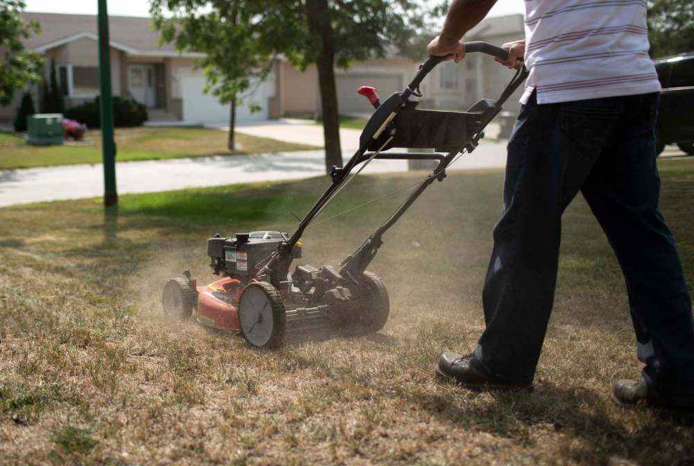 Jacky Maan, owner of Regal Grass, mows one of his customer’s overly dried out lawns in Linden Woods in August. (Andrew Ryan / Free Press files)