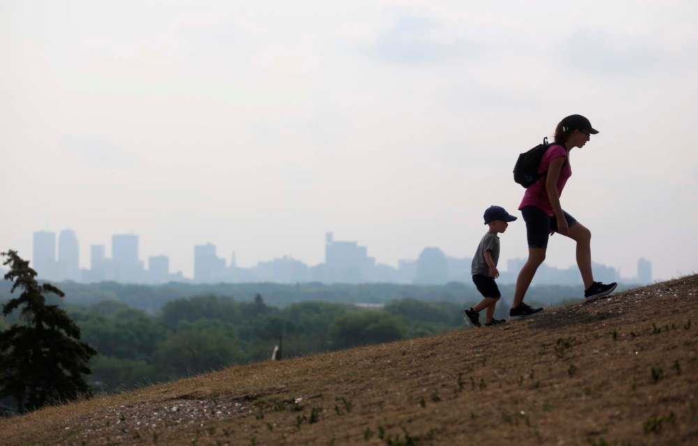 Allison Heinrichs and her son Kolton, 2, walk up Garbage Hill in front of smoke from forest fires in B.C. in August. (Trevor Hagan / Free Press files)