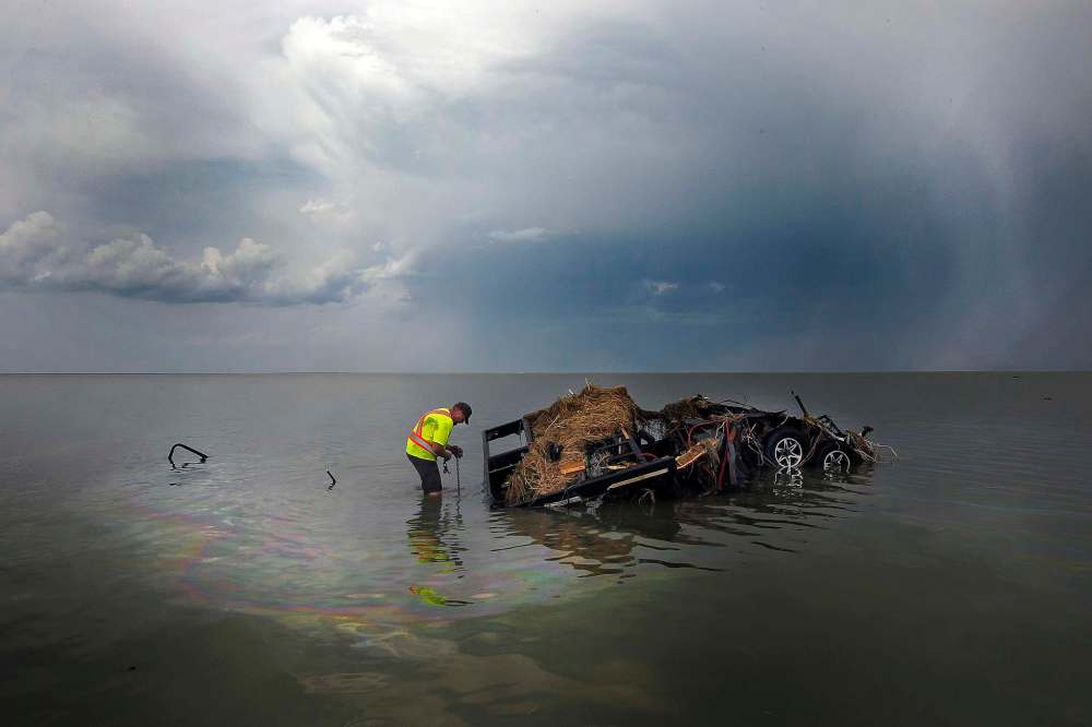Daniel Cottyn attaches a tow line to the wreckage of a camper in the lake at Margaret Bruce Beach and campground after a tornado hit the Alonsa area in August. (Phil Hossack / Free Press files)