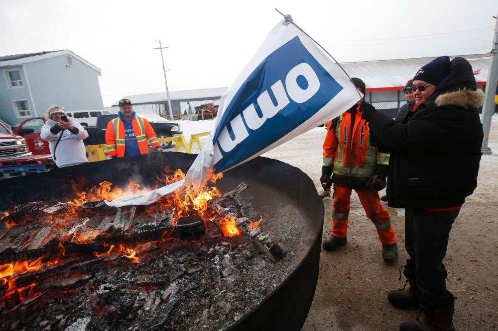 Patricia Kandiurin burns an Omnitrax banner at a party celebrating the opening of the repaired railway in Churchill. (John Woods / The Canadian Press)