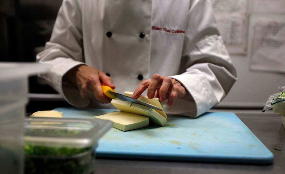 Sumruoy Poomrat cuts tofu.
