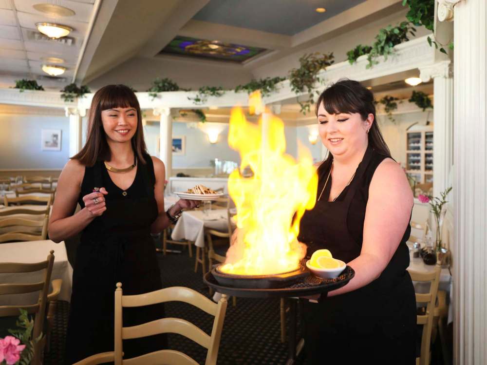 Long-time servers Jennie Bremner-McLeod (right) and Angida Ricafort in dining room serving saganaki.