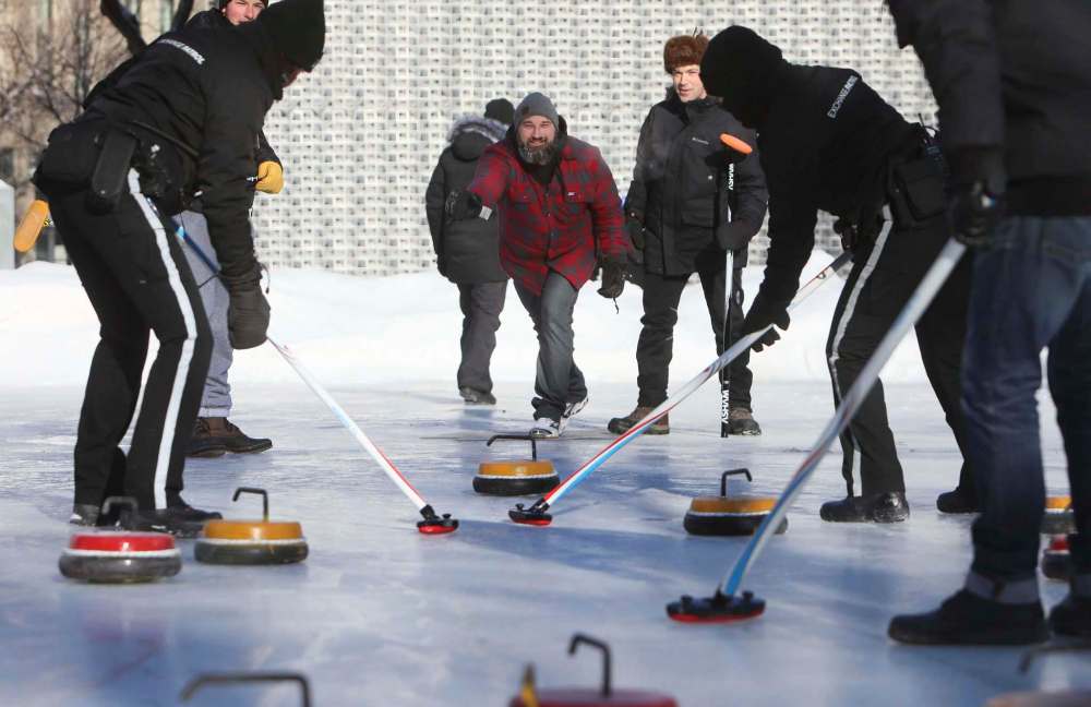 RUTH BONNEVILLE / WINNIPEG FREE PRESS
Business owner Nick Van Seggelen of Bodegoes throws a rock at the official opening of the outdoor rink at Old Market Square on Thursday. He was joined Mayor Brian Bowman and members of the Canadian junior curling team.