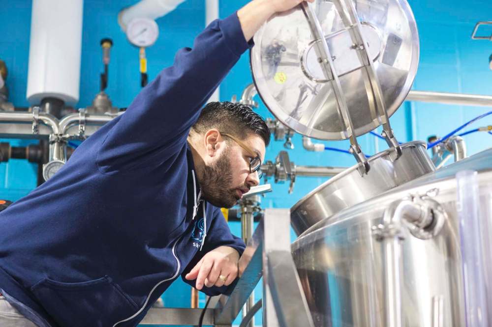 Sookram takes a look in the mash tun at his company’s Warsaw Avenue brewery.