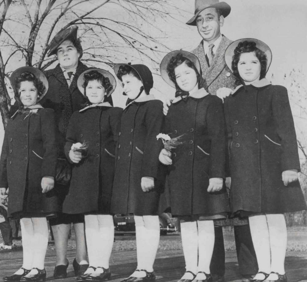 Elzire and Oliva Dionne (back, from left) stand with their quintuplets (from left) Cécile, Yvonne, Marie, Emilie and Annette. (The Canadian Press files)