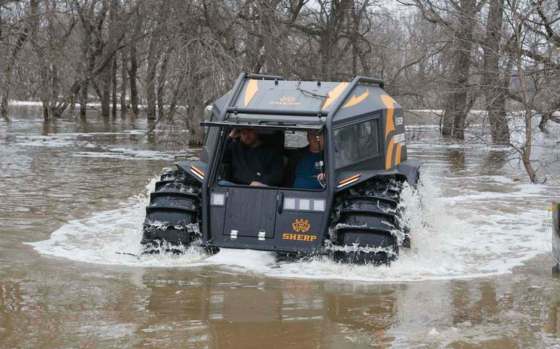 Sgt. Ben White, right, of the Williams County Sheriff's Office drives a Sherp all-terrain vehicle through water Saturday at a farm northeast of Harwood, N.D. The ATV floats in water and is used to help Cass County Sheriff's deputies assist residents during the flood. April Baumgarten / Forum News Service
