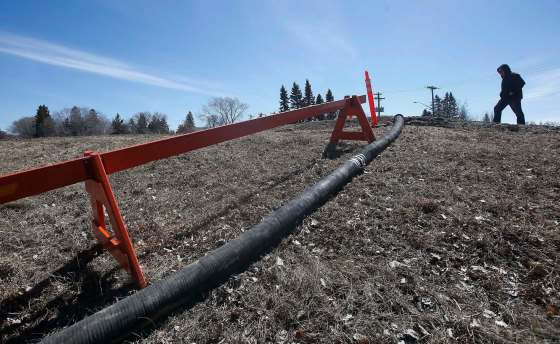 Jim Becker walks toward a hose crossing the town dike in Emerson Sunday. JOHN WOODS / WINNIPEG FREE PRESS