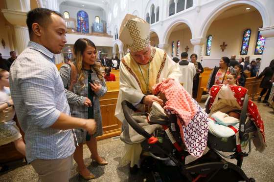 Richard Gagnon, archbishop of Winnipeg, greets parishioners Archie and Mary Ballesteros and newborn twins Anna and Hanna after Easter mass Sunday. Gagnon offered prayers for Sri Lanka, saying such violence has become 'all too frequent.'JOHN WOODS / WINNIPEG FREE PRESS