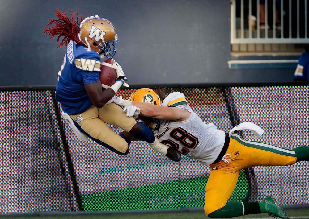 PHIL HOSSACK / WINNIPEG FREE PRESS
Blue Bombers receiver Lucky Whitehead leaps out of the grasp of Edmonton Eskimosdefender Kevin Francis to score the team’s second touchdown Thursday night.