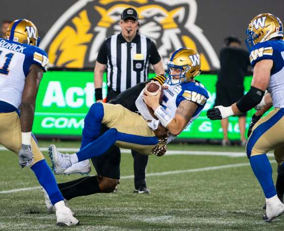 Matt Nichols is sacked by Hamilton Tiger-Cats defensive end Adrian Tracy in Hamilton, on Friday. (Peter Power / Canadian Press files)