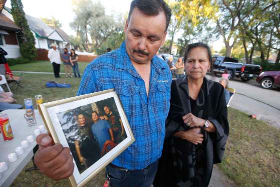 JOHN WOODS / WINNIPEG FREE PRESSEarl and Wanda Dano, parents of Michael Dano, hold a photo of Michael, right, his friend Lloyd, centre, and his brother, Cory, during a vigil Tuesday in front of 757 Chalmers Street East where Michael was found deceased. The police ruled it a suicide but the family is calling for further investigation.