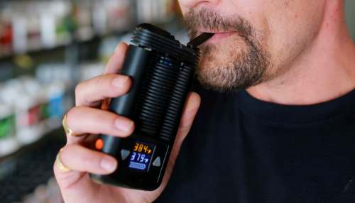 A man uses a hand-held dry-herb vaporizer, which heats cannabis without burning it.