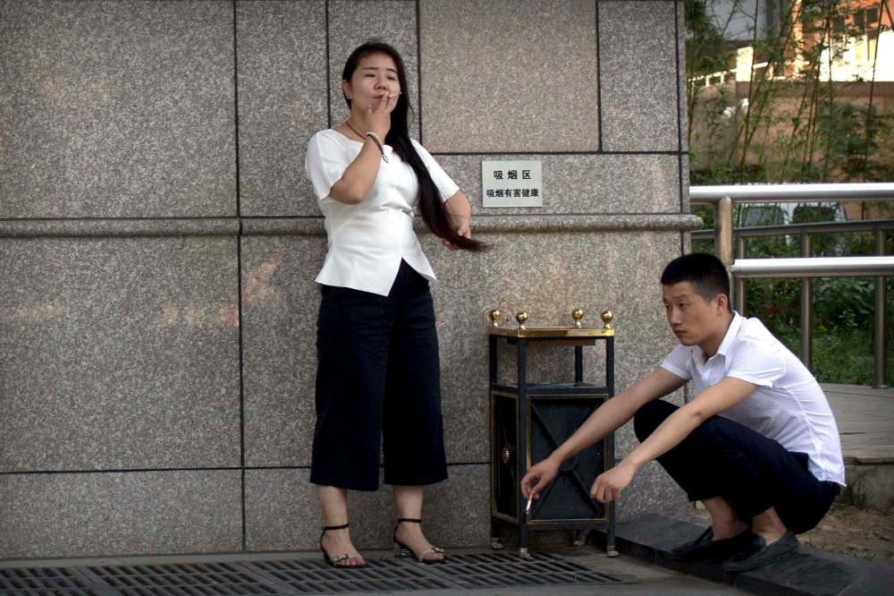 Mark Schiefelbein / The Associated Press FILE
A man and a woman smoke outside of an office building in Beijing. Most smokers in China, the world's largest consumer of tobacco, have no intention of kicking the habit and remain unaware of some of its most damaging health effects.
