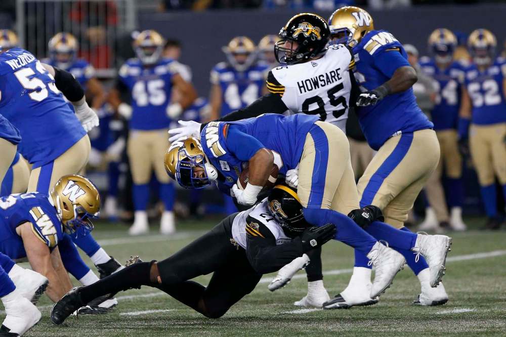 JOHN WOODS / THE CANADIAN PRESS
Bombers RB Andrew Harris (centre) gets tackled by Tiger-Cats' Simoni Lawrence.