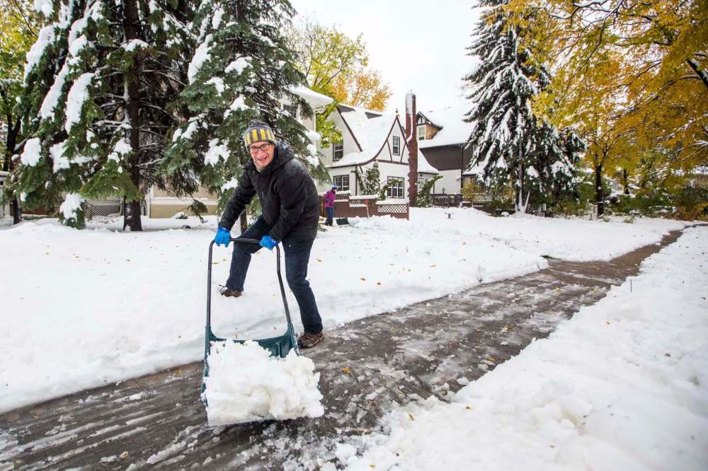 MIKAELA MACKENZIE / WINNIPEG FREE PRESS
David Firman shovels the wet, heavy snow from the sidewalk on Raglan Road on Saturday.