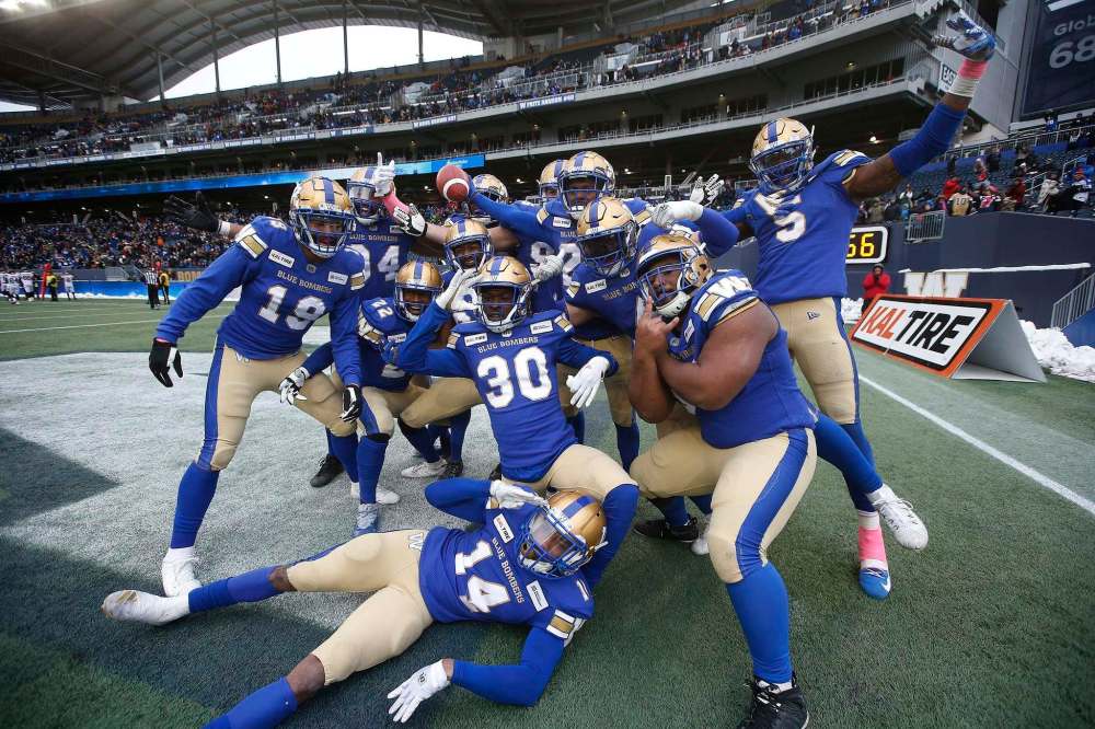 Nick Taylor (holding bal) and teammates celebrate his interception and touchdown on Saturday. (John Woods / The Canadian Press)
