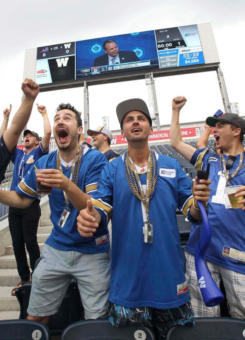 JOE BRYKSA / WINNIPEG FREE PRESS
Bombers and Jets fans Justin Rowank (from left), Cory Hiebert and Bryce Gauthier celebrate at Investor Group Field as Winnipeg Jets general manager Kevin Cheveldayoff (on monitor) announces his second-overall pick at the NHL Draft, Patrik Laine.