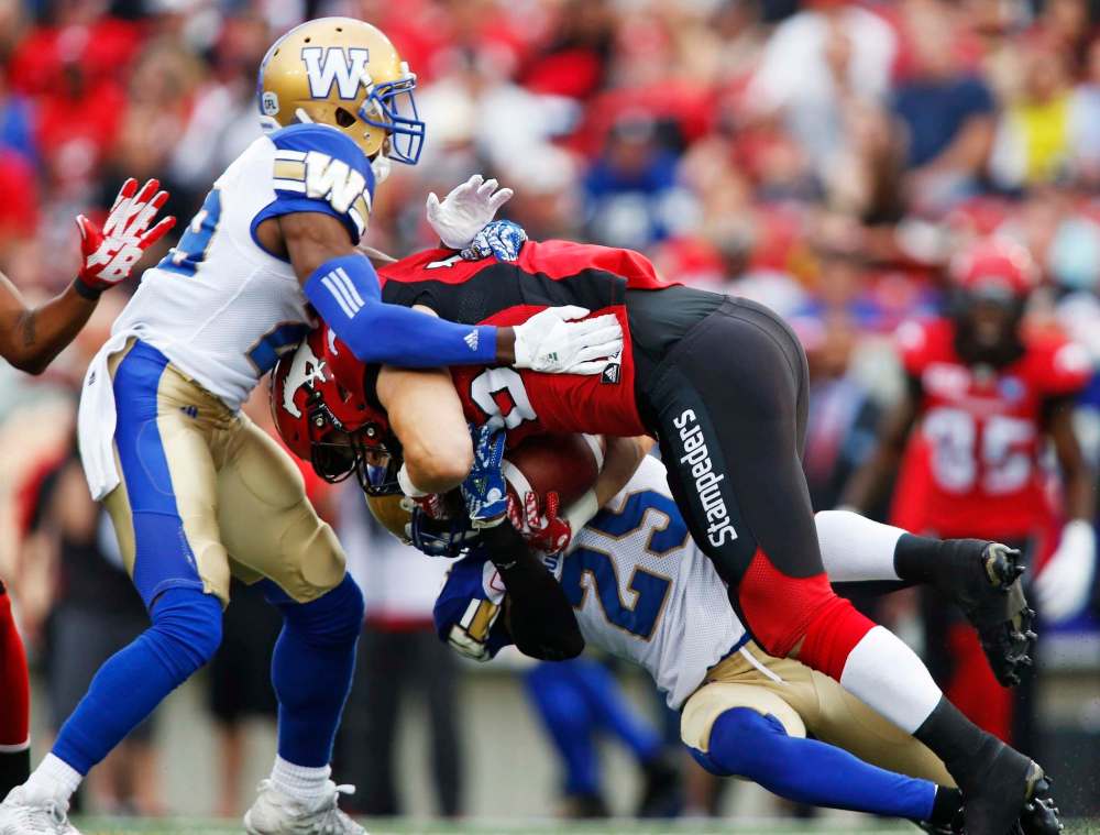 Jeff McIntosh / The Canadian Press
Calgary Stampeders' Rob Cote is tackled by Winnipeg Blue Bombers' Bruce Johnson (bottom) and Julian Posey during the first in Calgary Friday.