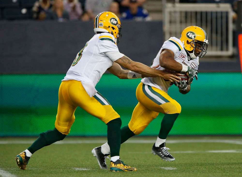 JOHN WOODS / THE CANADIAN PRESS
Edmonton Eskimos quarterback Mike Reilly (13) hands off to John White (30) during the second half of Thursday's game in Winnipeg.