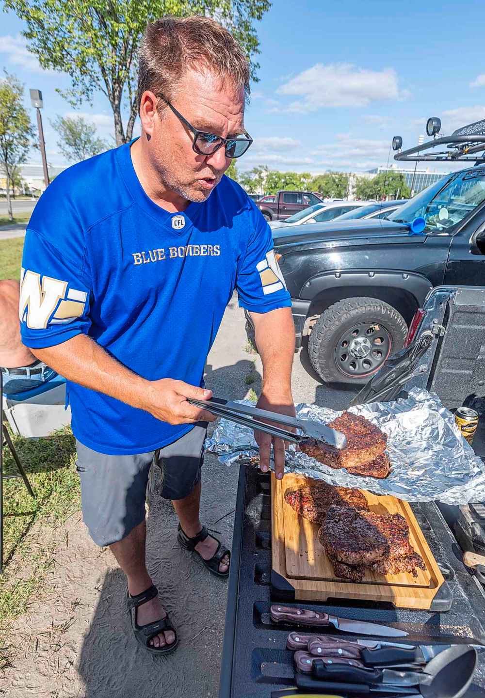 SASHA SEFTER / WINNIPEG FREE PRESS
Tailgater Michael Bisson serves up some smoked ribeye steaks from the bed of his pickup truck for his friends and family before the NFL pre-season game between the Green Bay Packers and Oakland Raiders at IG Field Thursday evening.