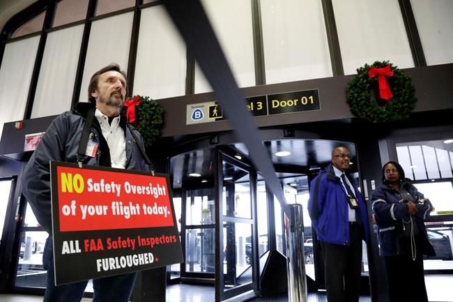 Federal Aviation Administration employee Michael Jessie, who is currently working without pay as an aviation safety inspector for New York international field office overseeing foreign air carriers, holds a sign while attending a news conference at Newark Liberty International Airport, Tuesday, Jan. 8, 2019, in Newark, N.J. U.S. Sen. Cory Booker and Sen. Bob Menendez called a news conference at the airport to address the partial government shutdown, which is keeping some airport employees working without pay. (AP Photo/Julio Cortez)