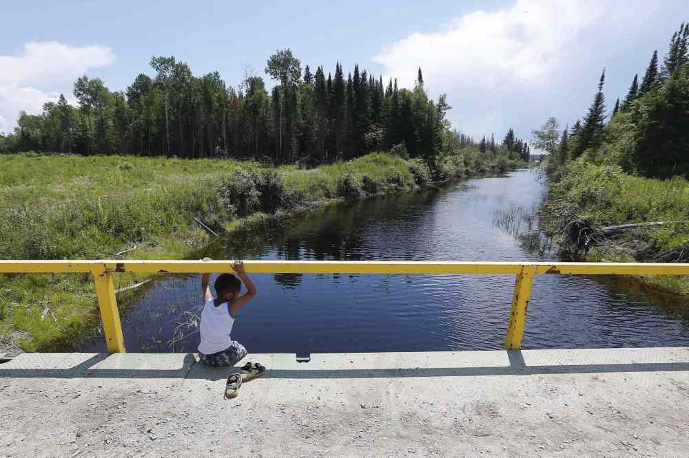 THE CANADIAN PRESS / JOHN WOODS
A boy from the Shoal Lake 40 First Nation sits on a bridge over a channel on on Thursday, June 25, 2015. crowdfunding campaign is underway to pay Ottawa's portion of an all-weather road for a reserve under one of the longest boil-water advisories in Canada.