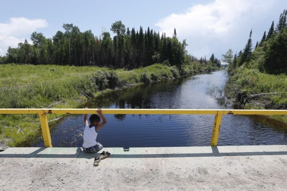 JOHN WOODS / The Canadian Press files A boy from the Shoal Lake 40 First Nation sits on a bridge over a channel in a file photo.