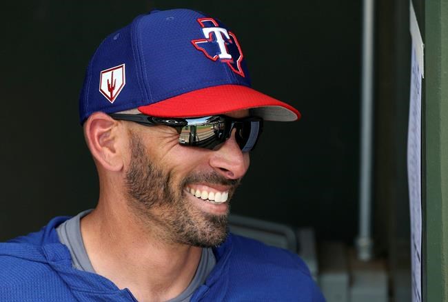 FILE - In this March 6, 2019, file photo, Texas Rangers manager Chris Woodward smiles as he talks with other coaches prior to a spring training baseball game against the San Francisco Giants, in Surprise, Ariz. First-year Texas manager Chris Woodward loves that the expectations are higher. At 42-36 just shy of the midpoint of the season, the Rangers haven’t lost any of their eight series over the past month. (AP Photo/Ross D. Franklin, File)