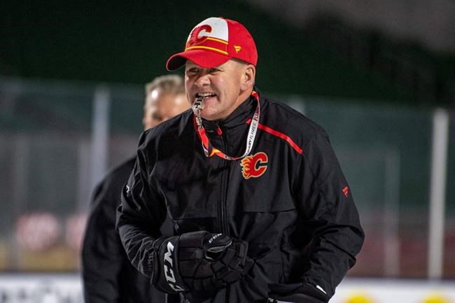 FILE - In this Oct. 25, 2019, file photo, Calgary Flames coach Bill Peters watches practice in Regina, Saskatchewan, ahead of the NHL Heritage Classic outdoor hockey game against the Winnipeg Jets. Calgary Flames general manager Brad Treliving said the team is looking into an accusation that head coach Bill Peters directed racial slurs toward a Nigerian-born hockey player a decade ago in the minor leagues, then arranged for the player’s demotion when he complained. Akim Aliu tweeted Monday, Nov. 25, 2019, that Peters “dropped the N bomb several times towards me in the dressing room in my rookie year because he didn’t like my choice of music.” (Liam Richards/The Canadian Press via AP, File)