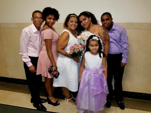 This Aug. 17, 2017 photo provided by Wendy Gomez, fourth from left, in April 2019 shows her wife, Wilnelia Cruz-Ulloa, third from left, with their children and stepchildren on their wedding day in New York. Cruz-Ulloa spent the last months of her life in a New York City ICU, waiting for a donated liver that never came. Doctors had urged the 38-year-old mother to move _ other states have more organs to go around. But she couldn't afford to. (Latisha Ozuna/Wendy Gomez via AP)
