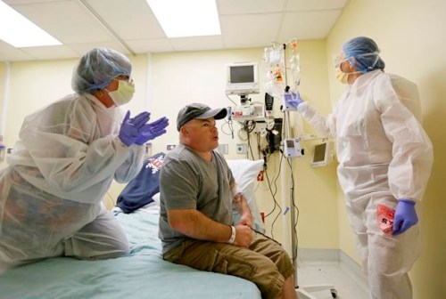 FILE - In this Monday, Nov. 13, 2017 file photo, Brian Madeux, starts to receive the first human gene editing therapy for Hunter syndrome, as his girlfriend, Marcie Humphrey, left, applauds at the UCSF Benioff Children's Hospital in Oakland, Calif. At right is nurse practitioner Jacqueline Madden. On Thursday, Feb. 7, 2019, scientists gave an update on the first effort to edit genes, or permanently change the DNA, of about a dozen adults, including Madeux, with metabolic diseases. (AP Photo/Eric Risberg)