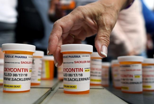 FILE - In this Aug. 17, 2018 file photo, family and friends who have lost loved ones to OxyContin and opioid overdoses leave pill bottles in protest outside the headquarters of Purdue Pharma, which is owned by the Sackler family, in Stamford, Conn. The company that has made billions selling the prescription painkiller OxyContin says it is considering bankruptcy as one of several possible legal options, in an email to The Associated Press. (AP Photo/Jessica Hill, File)