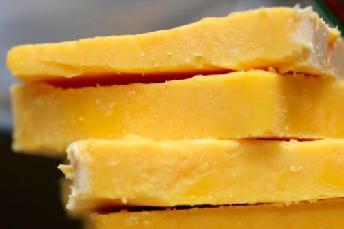 FILE - This May 28, 2015 file photo shows cheddar cheese Madison, Wis. The practice of adding color to cheddar cheese reaches back to when cheesemakers in England skimmed the butterfat from milk to make butter, according to Elizabeth Chubbuck of Murray‚Äôs Cheese in New York. The leftover milk was whiter, so pigments were added to recreate butterfat‚Äôs golden hue, she said. (Amber Arnold/Wisconsin State Journal via AP)