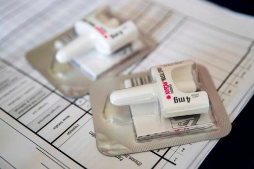 FILE - In this Tuesday, July 3, 2018 file photo, a Narcan nasal device which delivers naloxone lies on a counter as a health educator gives instructions on how to administer it in the Brooklyn borough of New York. On Wednesday, Dec. 19, 2018, the U.S. government told doctors to consider prescribing the overdose antidote naloxone to many more patients who take opioid painkillers. (AP Photo/Mary Altaffer)
