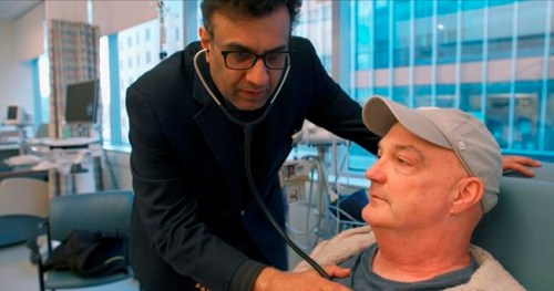 In this February 2019 photo provided by Brigham and Women's Hospital, Dr. Mandeep Mehra, executive director of Brigham‚Äôs Center for Advanced Heart Disease, checks on patient James Sullivon at the hospital in Boston. Sullivon, who received a hepatitis C-positive heart transplant, was given antiviral medicine shortly after the procedure in hopes of blocking hepatitis C infection rather than having to treat it. (Adam Knee/Brigham and Women's Hospital via AP)