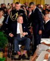Former President George H.W. Bush, in a pair of red and white socks, is wheeled off of the stage to sit next to President Barack Obama after presenting the 5,000th Daily Point of Light Award at the White House in Washington on July 15, 2013. (AP Photo/Susan Walsh, File)