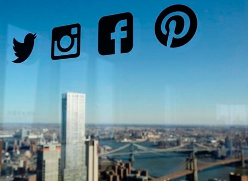 FILE- In this Jan. 13, 2016, file photo, Icons for Twitter, Instagram, Facebook and Pinterest are displayed on a window in New York. Nearly half of U.S. households carry credit card debt, which means many of the friends making you jealous on Instagram may not be able to afford the vacations they post about. (AP Photo/Mark Lennihan, File)