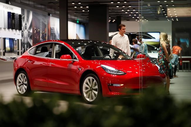 FILE- In this July 6, 2018, file photo, a prospective customer confer with sales associate as a Model 3 sits on display in a Tesla showroom in the Cherry Creek Mall in Denver. On Tuesday, Jan. 1, 2019, the federal credit for Tesla buyers dropped from $7,500 to $3,750. It will gradually be phased out this year. (AP Photo/David Zalubowski, File)
