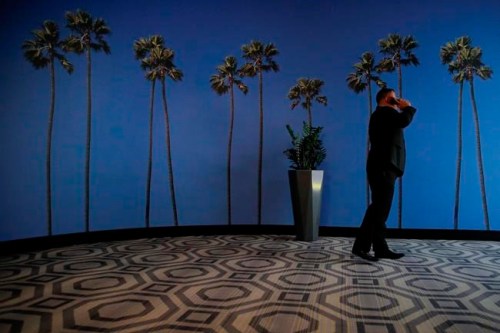 FILE - In this May 4, 2018, file photo a man talks on the phone in a hallway adorned with the palm tree-printed wallpaper at a hotel near the Los Angeles International Airport in Los Angeles. U.S. regulators are proposing new measures intended to thwart billions of annoying robocalls received by Americans each year. The rising volume of unwanted calls in the last few years has created pressure on Congress, regulators and phone companies to do something to act. (AP Photo/Jae C. Hong, File)