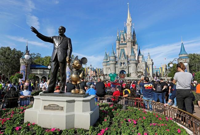 FILE - In this Jan. 9, 2019, file photo, guests watch a show near a statue of Walt Disney and Micky Mouse in front of the Cinderella Castle at the Magic Kingdom at Walt Disney World in Lake Buena Vista, Fla. Disney Plus says it hit more than 10 million sign-ups on its first day of launch, far exceeding expectations. Disney’s mix of Marvel and Star Wars movies and shows, classic animated films and new series appears to be a hit out of the gate after its launch on Tuesday, Nov. 12. (AP Photo/John Raoux, File)