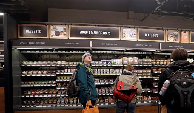 FILE - In this Jan. 22, 2018, file photo, a customer looks overhead in an Amazon Go store, where sensors and cameras are part of a system used to tell what people have purchased and charge their Amazon account in Seattle. A small number of restaurants and stores are going cash-free in the U.S., looking to cater to customers who increasingly pay with a card or smartphone. But a backlash is growing against the practice that some say discriminates against those who lack back accounts or rely on cash for most of their daily transactions. (AP Photo/Elaine Thompson, File)