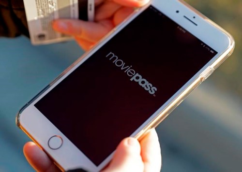 FILE- In this Jan. 30, 2018, file photo, Cassie Langdon uses to her phone to launch the MoviePass app to see what movies are available at AMC Indianapolis 17 theatre in Indianapolis. Several Netflix-like subscription plans offer movie theater tickets for a monthly fee. But these plans come with restrictions. Plans from MoviePass and Sinemia work at most theaters. MoviePass, however, restricts what you can watch under its cheapest plans. (AP Photo/Darron Cummings, File)