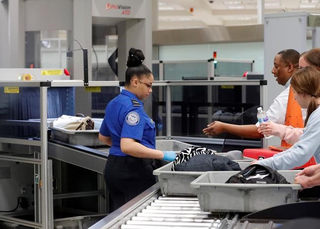 FILE - In this Jan. 7, 2019 file photo, a Transportation Security Administration employee helps air travelers submit their bags for inspection at Hartsfield-Jackson Atlanta International Airport in Atlanta. The world’s busiest airport is seeing some of the nation’s longest wait times to get through security, just nine days before it expects 150,000 out-of-town visitors for the Super Bowl. The Transportation Security Administration on Friday, Jan. 25 said Hartsfield-Jackson Atlanta International Airport had maximum wait times Thursday of 42 minutes, the highest of the nation’s top 42 airports. (AP Photo/John Bazemore, File)
