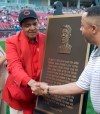 FILE - In this April 20, 2004, file photo, former Cincinnati Reds player Chuck Harmon, left, reaches across a plaque honoring him to shake hands with his son, Chuck Harmon Jr., during ceremonies before the Reds game against the Atlanta Braves in Cincinnati. Harmon, the Reds' first African-American player, died Tuesday, March 19, 2019. He was 94. (AP Photo/Al Behrman, File)