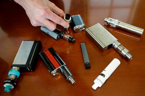FILE - In this April 10, 2018, file photo, a high school principal displays vaping devices that were confiscated from students in such places as restrooms or hallways at the school in Massachusetts. The U.S. surgeon general says swift action is needed to prevent millions of teenagers and adolescents from becoming hooked on Juul and other high-nicotine electronic cigarettes. Surgeon General Jerome Adams said Tuesday, Dec. 18, that parents, teachers and physicians must take aggressive steps to address an epidemic of underage vaping. (AP Photo/Steven Senne, File)